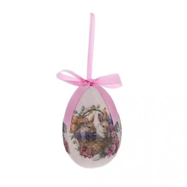 Decorazione pasquale a forma di uovo rosa pastello firmata Blanc Mariclò con nastro in raso coordinato. Il decoro centrale in stile vintage illustra due coniglietti bianchi all'interno di un cesto intrecciato, circondati da una ricca ghirlanda di fiori rosa e viola.