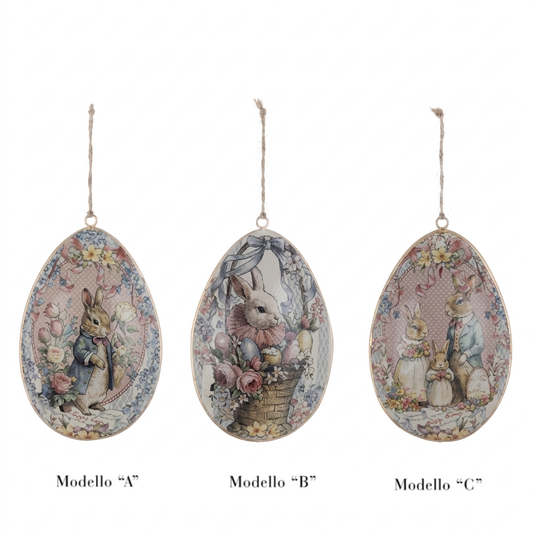 Tre varianti assortite di uova di Pasqua decorative in metallo da appendere della collezione "Joyeuses Paques" di Blanc Mariclo'. I pendenti, sorretti da uno spago rustico, mostrano tre diverse illustrazioni vintage contrassegnate come Modello A (coniglio singolo), Modello B (coniglio nel cesto) e Modello C (famiglia di coniglietti), perfette per creare un albero di Pasqua in stile shabby chic.