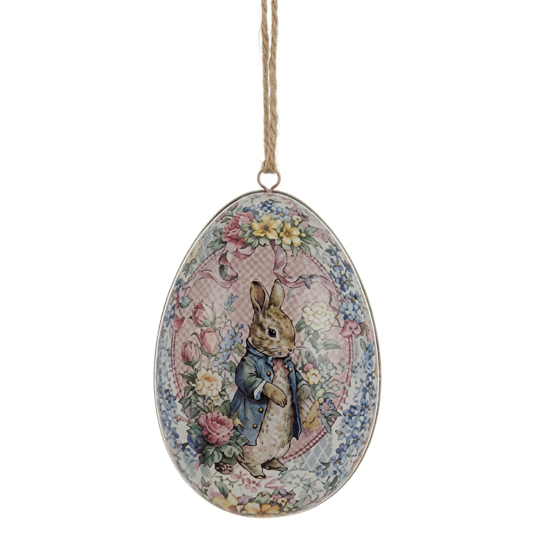 Uovo di Pasqua decorativo in metallo da appendere della linea "Joyeuses Paques" firmata Blanc Mariclo'. Il pendente è impreziosito da un'illustrazione vintage stile Beatrix Potter raffigurante un coniglietto con giacca azzurra inserito in un medaglione floreale rosa e completato da una cornice di fiorellini azzurri e gialli.