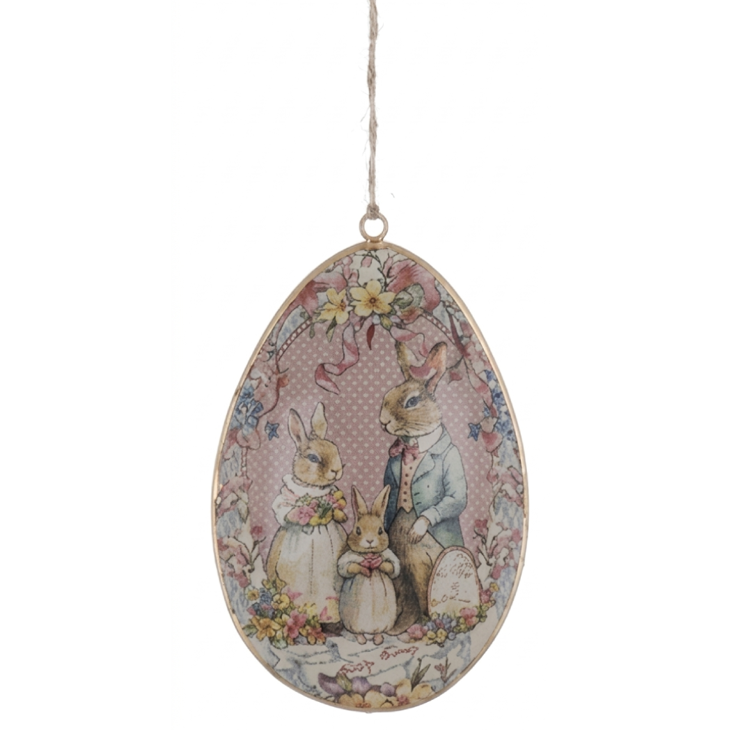 Uovo decorativo in metallo con spago della collezione pasquale "Joyeuses Paques" di Blanc Mariclo'. La stampa vintage mostra una graziosa famiglia di tre coniglietti vestiti a festa su uno sfondo a pois rosa racchiuso da ghirlande di fiori, ideale per arricchire composizioni primaverili o addobbare rami di pesco per la Pasqua.
