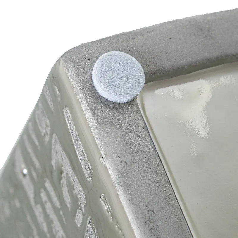 Vaso a bottiglia rettangolare verticale firmato Camacho, caratterizzato da un'elegante finitura ceramica color argento lucido con una texture a rilievo finemente lavorata e un originale design geometrico irregolare con foro centrale vuoto. Questo moderno complemento d'arredo è provvisto di un collo stretto superiore ideale per ospitare singoli steli floreali, perfetto come sofisticato oggetto ornamentale per impreziosire mobili, consolle o tavoli in contesti contemporanei.