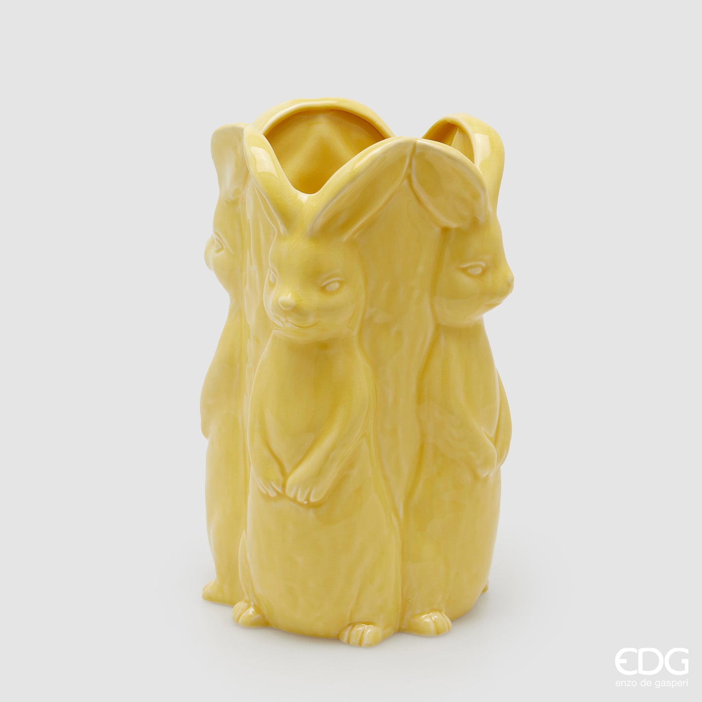Vaso decorativo alto EDG Enzo De Gasperi linea Easter in ceramica giallo pastello. Design scultoreo composto da tre grandi conigli a figura intera che formano il corpo del vaso. Altezza 30 cm, stile elegante per la Pasqua.