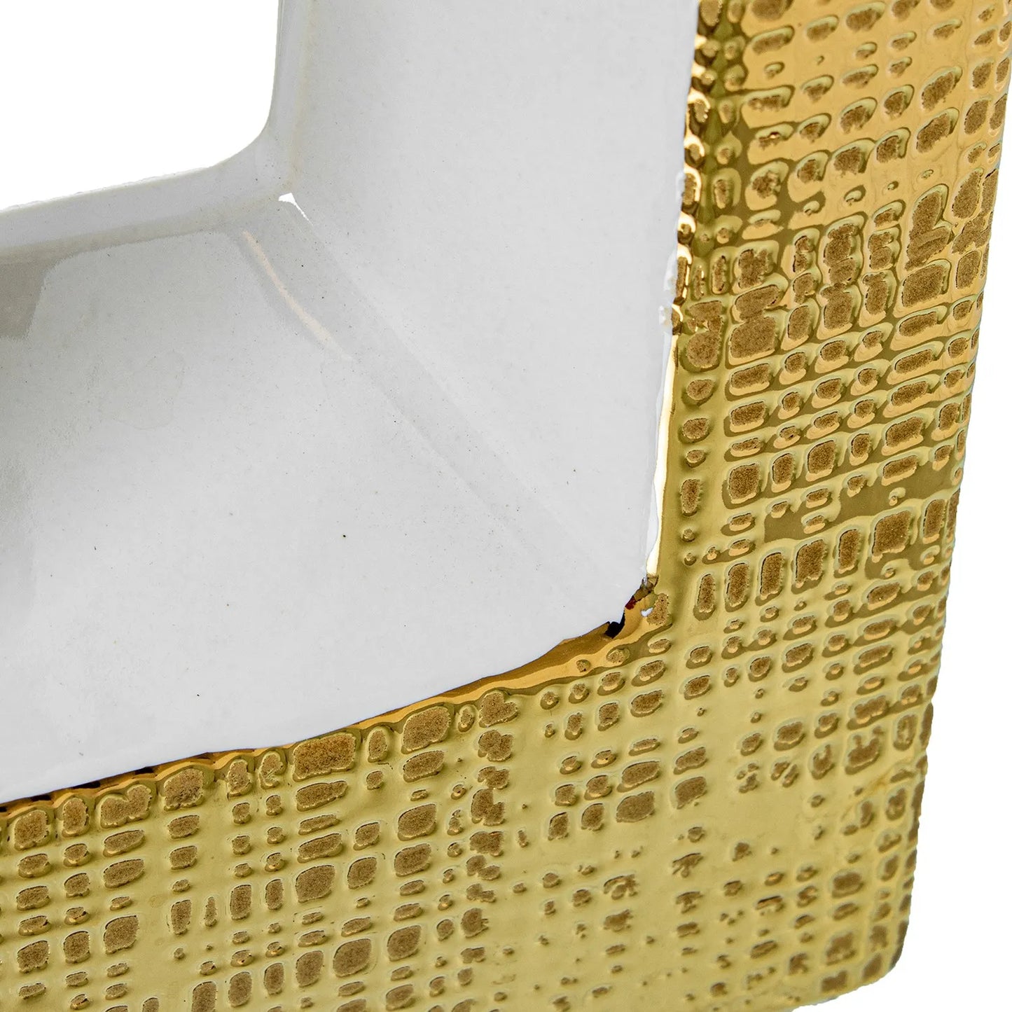 Vaso a bottiglia rettangolare verticale firmato Camacho, caratterizzato da un'elegante finitura ceramica color oro lucido con una texture a rilievo finemente lavorata, dettagli bianchi e un originale design geometrico con foro centrale vuoto. Questo moderno complemento d'arredo è provvisto di un collo stretto superiore ideale per ospitare singoli steli floreali, perfetto come sofisticato oggetto ornamentale per impreziosire mobili, consolle o tavoli in contesti contemporanei.