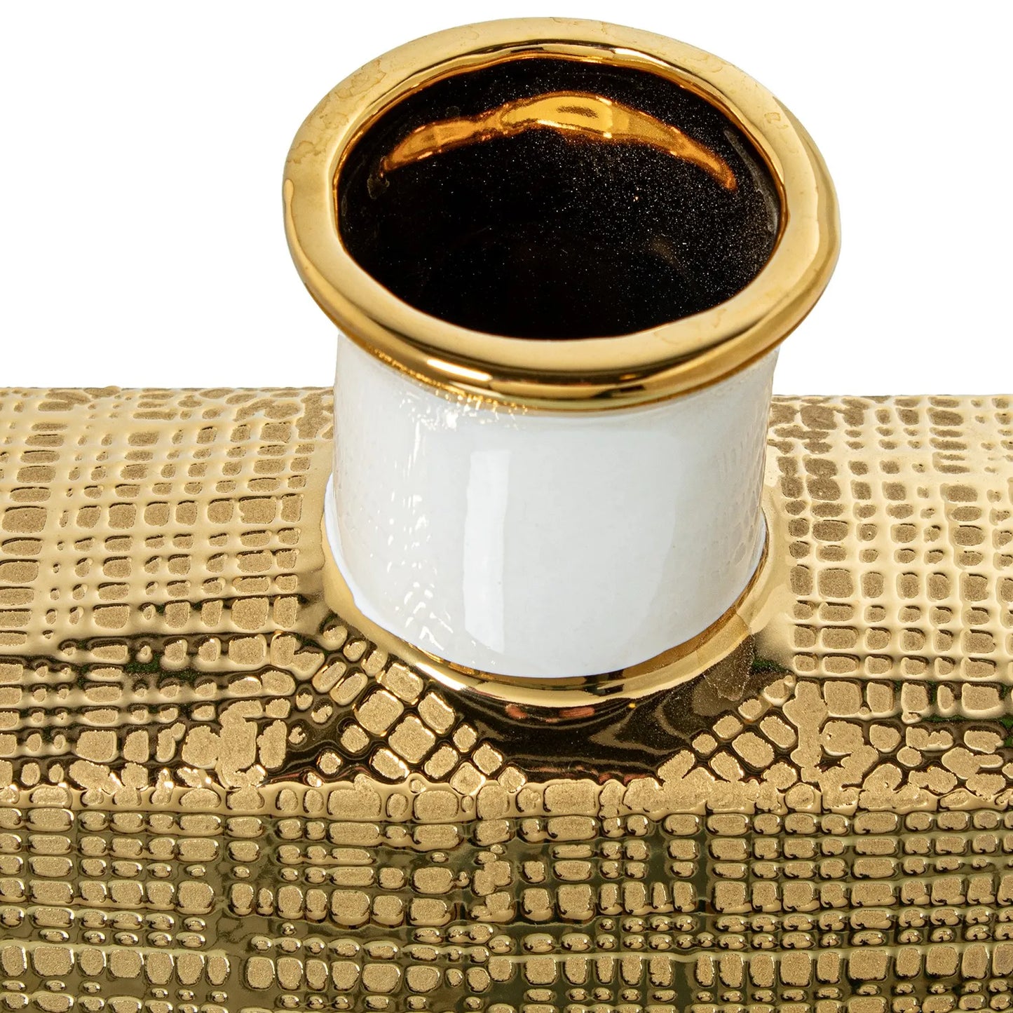 Vaso a bottiglia rettangolare verticale firmato Camacho, caratterizzato da un'elegante finitura ceramica color oro lucido con una texture a rilievo finemente lavorata, dettagli bianchi e un originale design geometrico con foro centrale vuoto. Questo moderno complemento d'arredo è provvisto di un collo stretto superiore ideale per ospitare singoli steli floreali, perfetto come sofisticato oggetto ornamentale per impreziosire mobili, consolle o tavoli in contesti contemporanei.