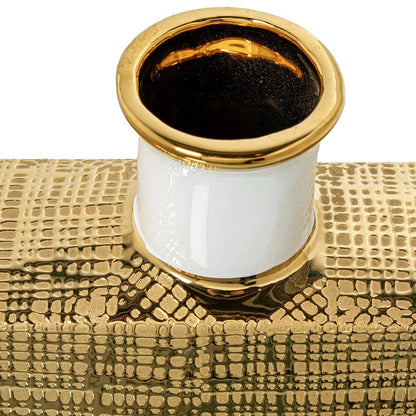 Vaso a bottiglia rettangolare verticale firmato Camacho, caratterizzato da un'elegante finitura ceramica color oro lucido con una texture a rilievo finemente lavorata, dettagli bianchi e un originale design geometrico con foro centrale vuoto. Questo moderno complemento d'arredo è provvisto di un collo stretto superiore ideale per ospitare singoli steli floreali, perfetto come sofisticato oggetto ornamentale per impreziosire mobili, consolle o tavoli in contesti contemporanei.