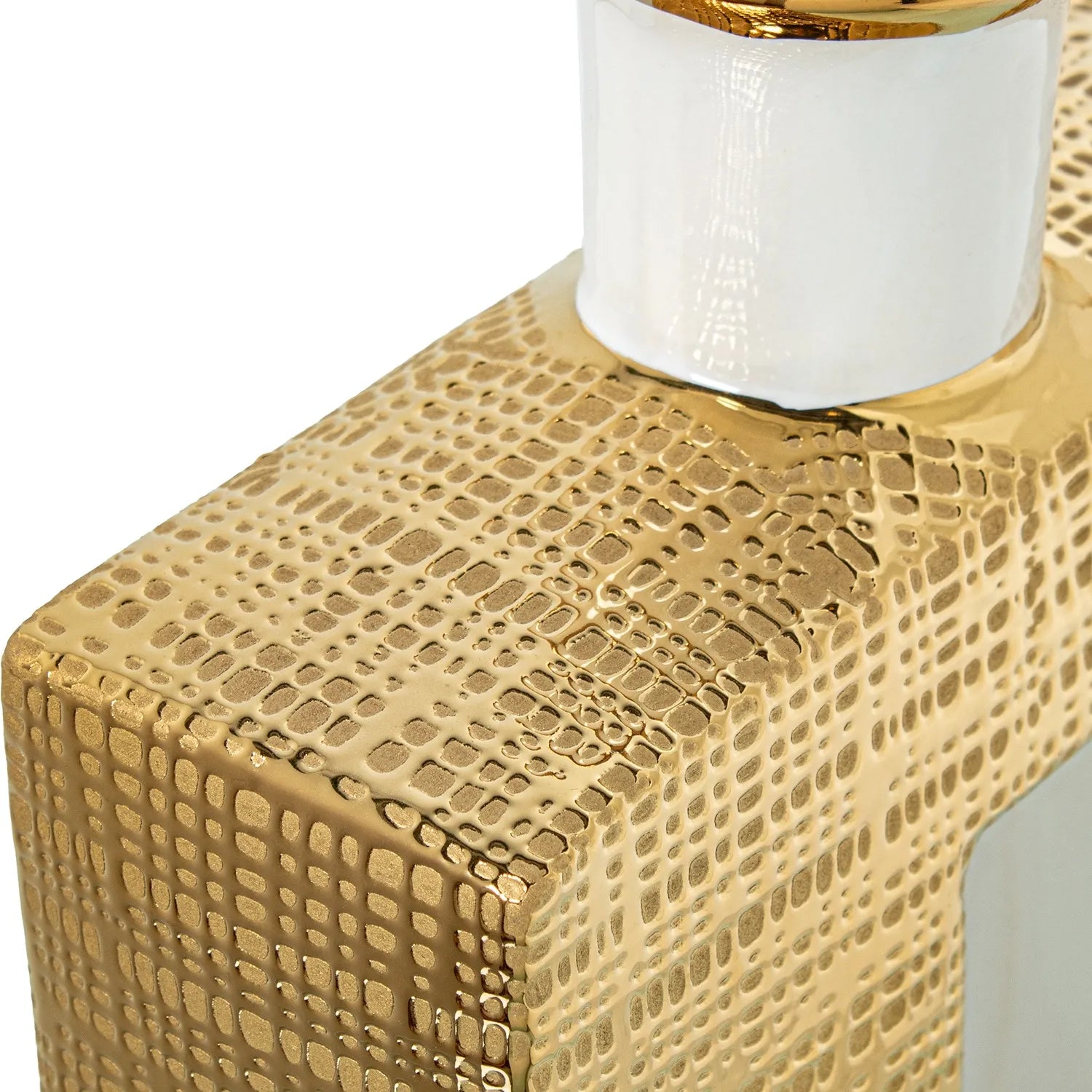 Vaso a bottiglia rettangolare verticale firmato Camacho, caratterizzato da un'elegante finitura ceramica color oro lucido con una texture a rilievo finemente lavorata, dettagli bianchi e un originale design geometrico con foro centrale vuoto. Questo moderno complemento d'arredo è provvisto di un collo stretto superiore ideale per ospitare singoli steli floreali, perfetto come sofisticato oggetto ornamentale per impreziosire mobili, consolle o tavoli in contesti contemporanei.